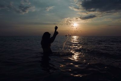 Silhouette man standing by sea against sky during sunset