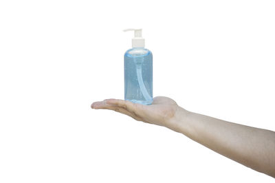 Close-up of hand holding bottle against white background