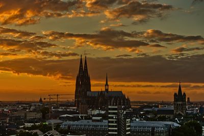 Buildings in city against romantic sky at sunset