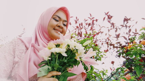 Close-up of bride with flowers against clear sky