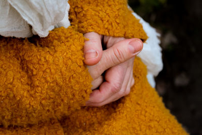 Midsection of woman wearing warm clothing with hands clasped outdoors