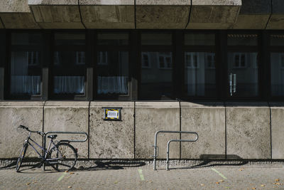 Bicycle by footpath against buildings in city