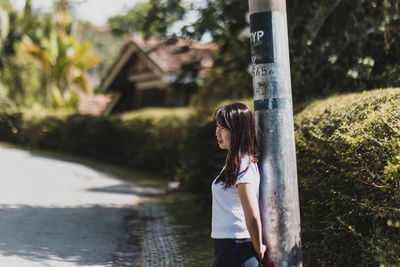 Side view of woman standing against trees