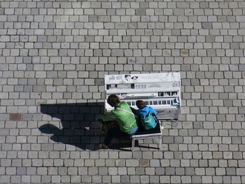 High angle view of people sitting on cobblestone street