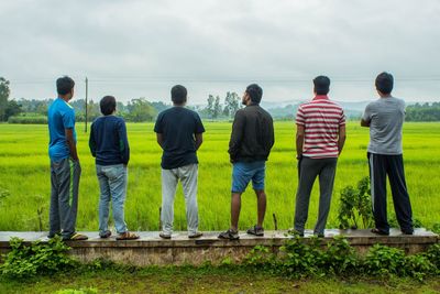 Rear view of people standing on water against sky