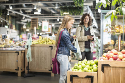 Mother and daughter buying apples in supermarket