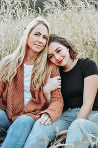 Portrait of smiling women sitting on land against plants