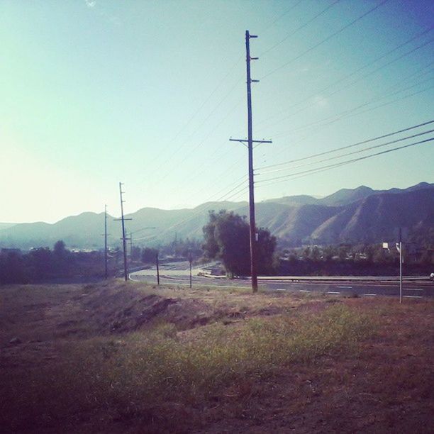 mountain, mountain range, landscape, electricity pylon, tranquility, tranquil scene, power line, sky, scenics, electricity, road, nature, beauty in nature, clear sky, non-urban scene, countryside, power supply, connection, grass, transportation