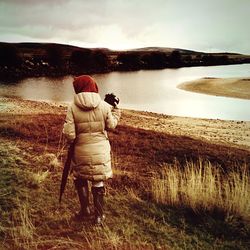 Rear view of man photographing on field against sky