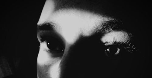 Close-up of young woman against black background