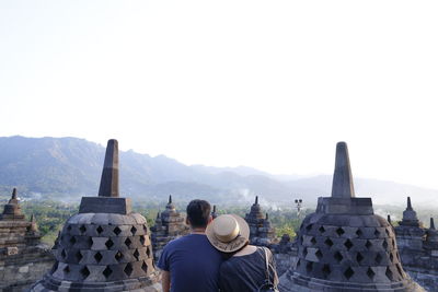 Rear view of couple looking at temple against clear sky