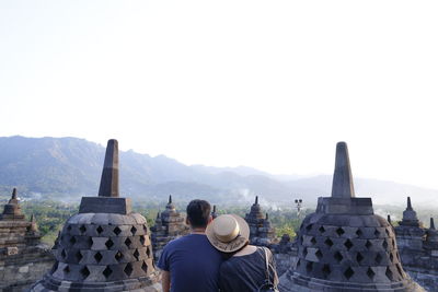 Rear view of man looking at temple against clear sky