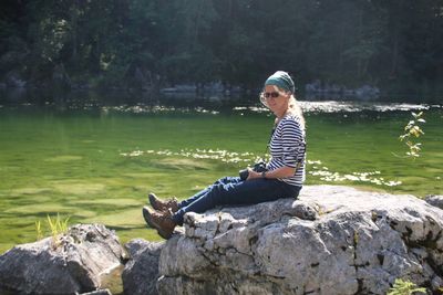 Woman sitting on rock by lake