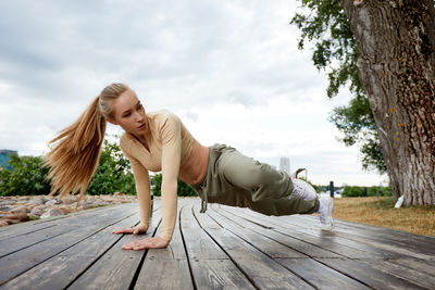 Side view of woman sitting on wooden wall