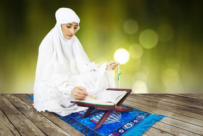 Woman reading book while sitting on table