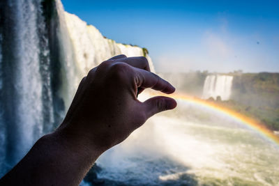 Close-up of hand rainbow by waterfall