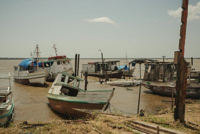 Fishing boats moored at harbor against sky