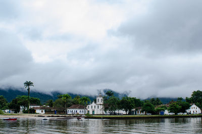 Scenic view of river by buildings against sky