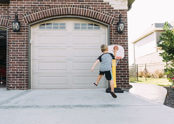 Rear view of boy playing basketball on driveway