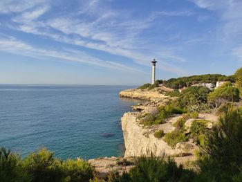 Lighthouse by sea against sky