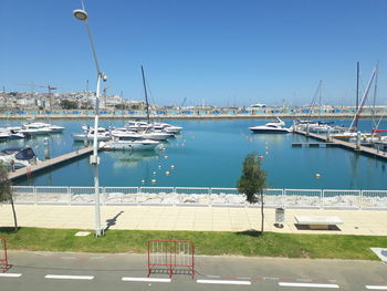 Sailboats moored at harbor against clear blue sky