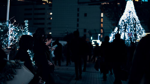 People on illuminated street in city at night
