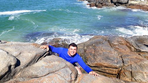 High angle portrait of man on rock against sea