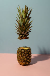 Pineapple sliced with one half floating on dual tone background. creative fruit concept