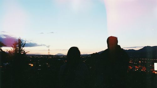 Silhouette of people in city against sky