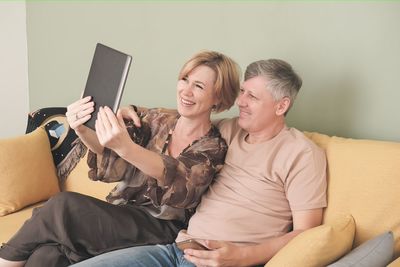 Friends using mobile phone while sitting on sofa at home