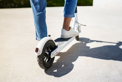 Low section of person riding push scooter on road