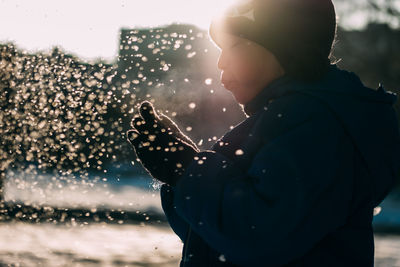 Side view of child in park during winter with snowflakes 
