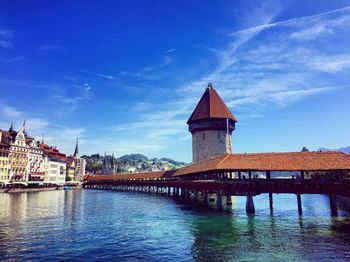 View of temple by river against blue sky