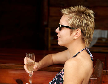 Side view of woman holding champagne while sitting at restaurant