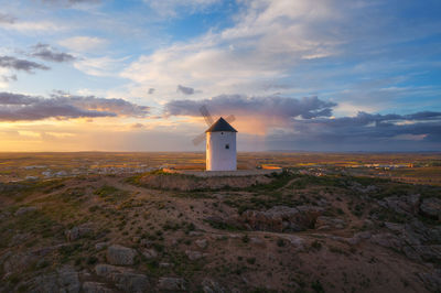 Lighthouse by sea against sky during sunset