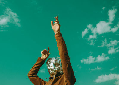 Low angle view of man with arms raised against blue sky