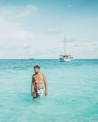 Full length of shirtless man in sea against sky