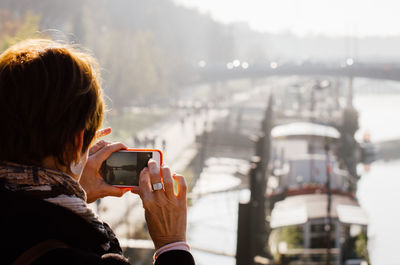 Rear view of woman using mobile phone in city