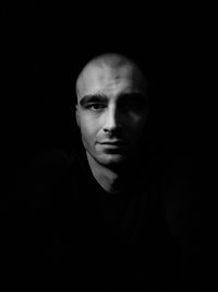 Portrait of young man against black background