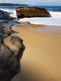 Rocks on beach by sea against sky