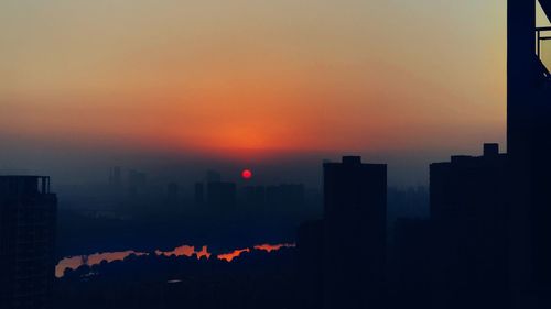 Silhouette buildings against sky during sunset