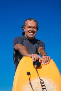 Low angle portrait of man against blue sky