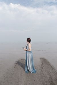 Full length of young woman using phone on beach