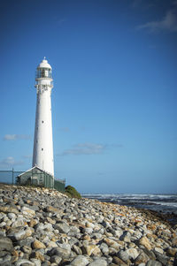 Lighthouse by sea against sky