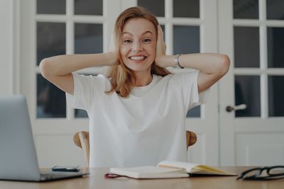 Portrait of young woman using mobile phone while sitting on table