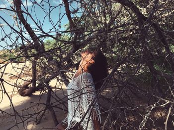 Low angle view of woman standing by tree against sky