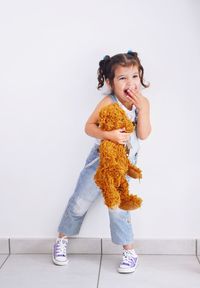 Full length portrait of cute girl standing against white background