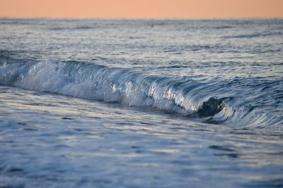 Close-up of wave on sea against sky during sunset