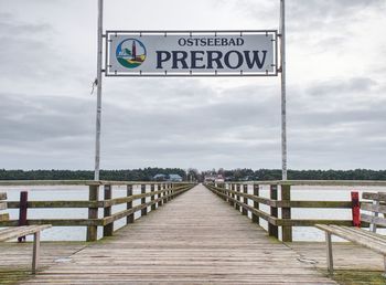 Information sign on pier against sky