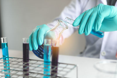 Midsection of scientist with chemicals at laboratory